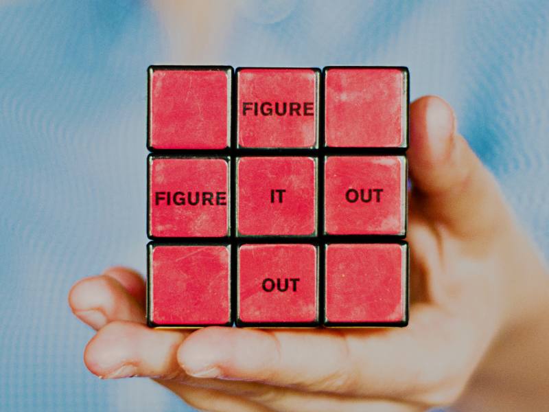 Rubik's cube has all red sides showing and reads 'figure it out' vertically and horizontally.